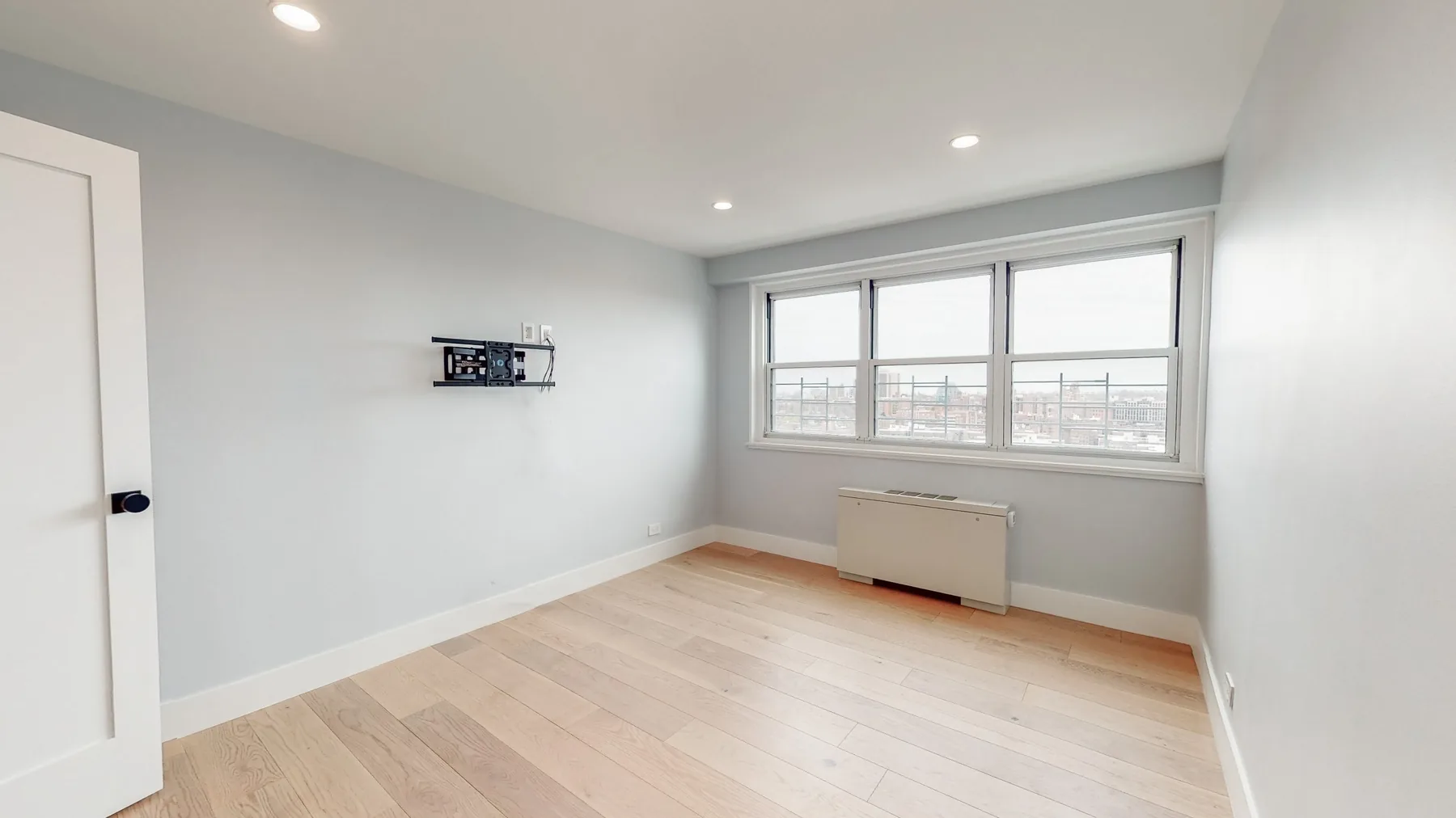 A bright, freshly finished room with recessed lighting and a wall-mounted control
