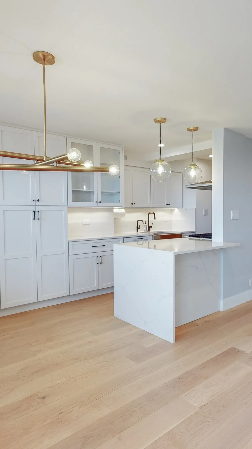 A white kitchen with pendant lights over the island and under-cabinet lighting
