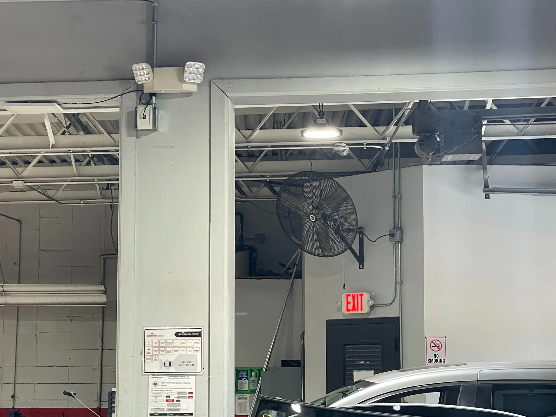 A commercial garage ceiling with new LED lighting and an exit sign
