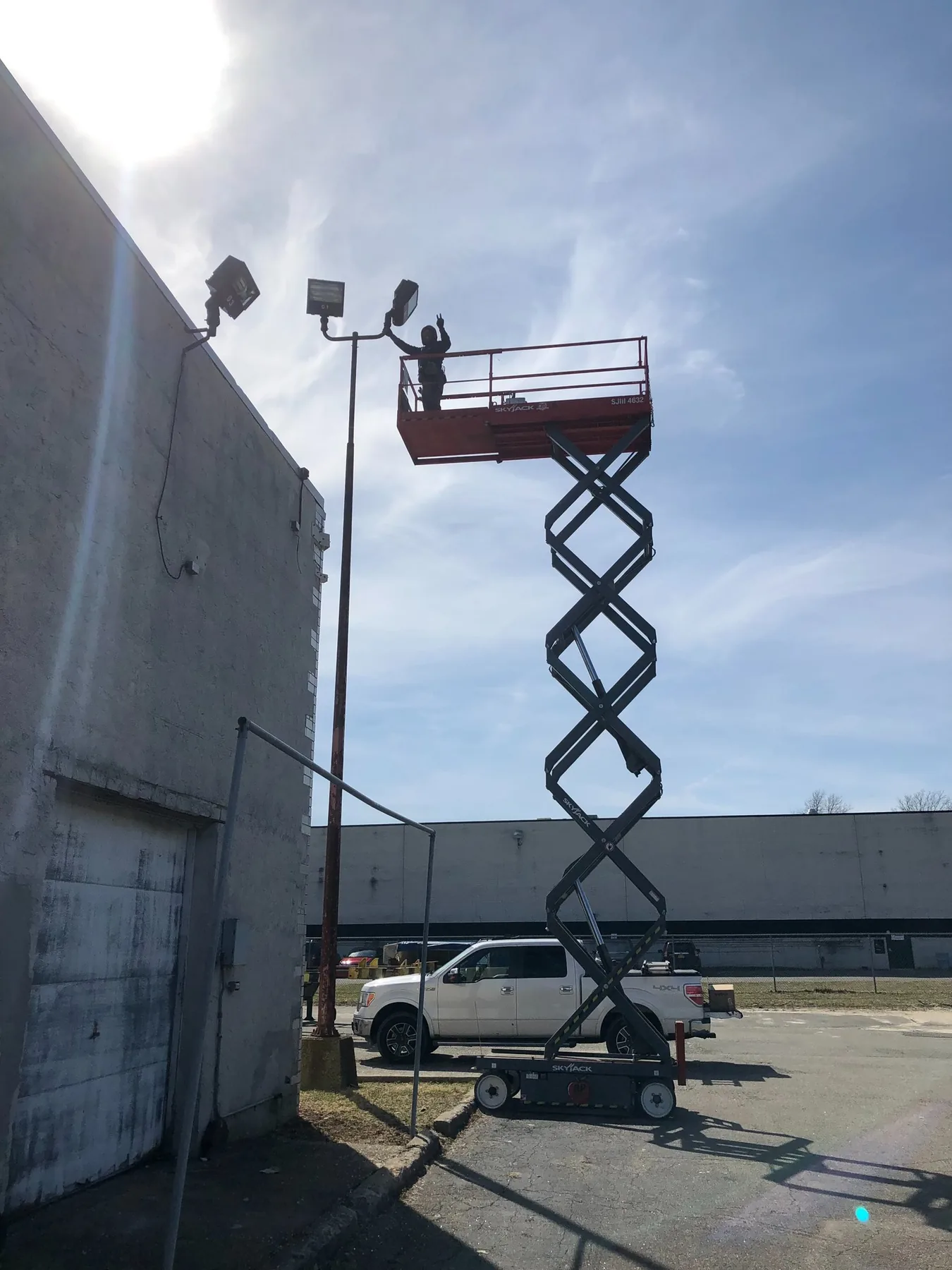 Exterior light fixtures installed on a masonry wall from a scissor lift
