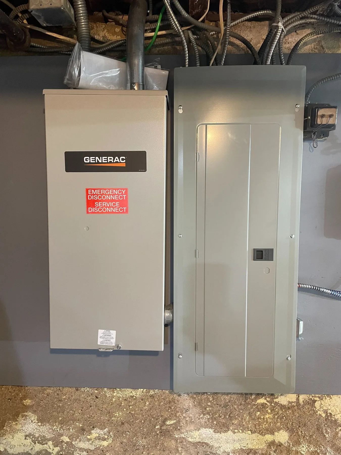 A Generac automatic transfer switch installed beside a main electrical panel
