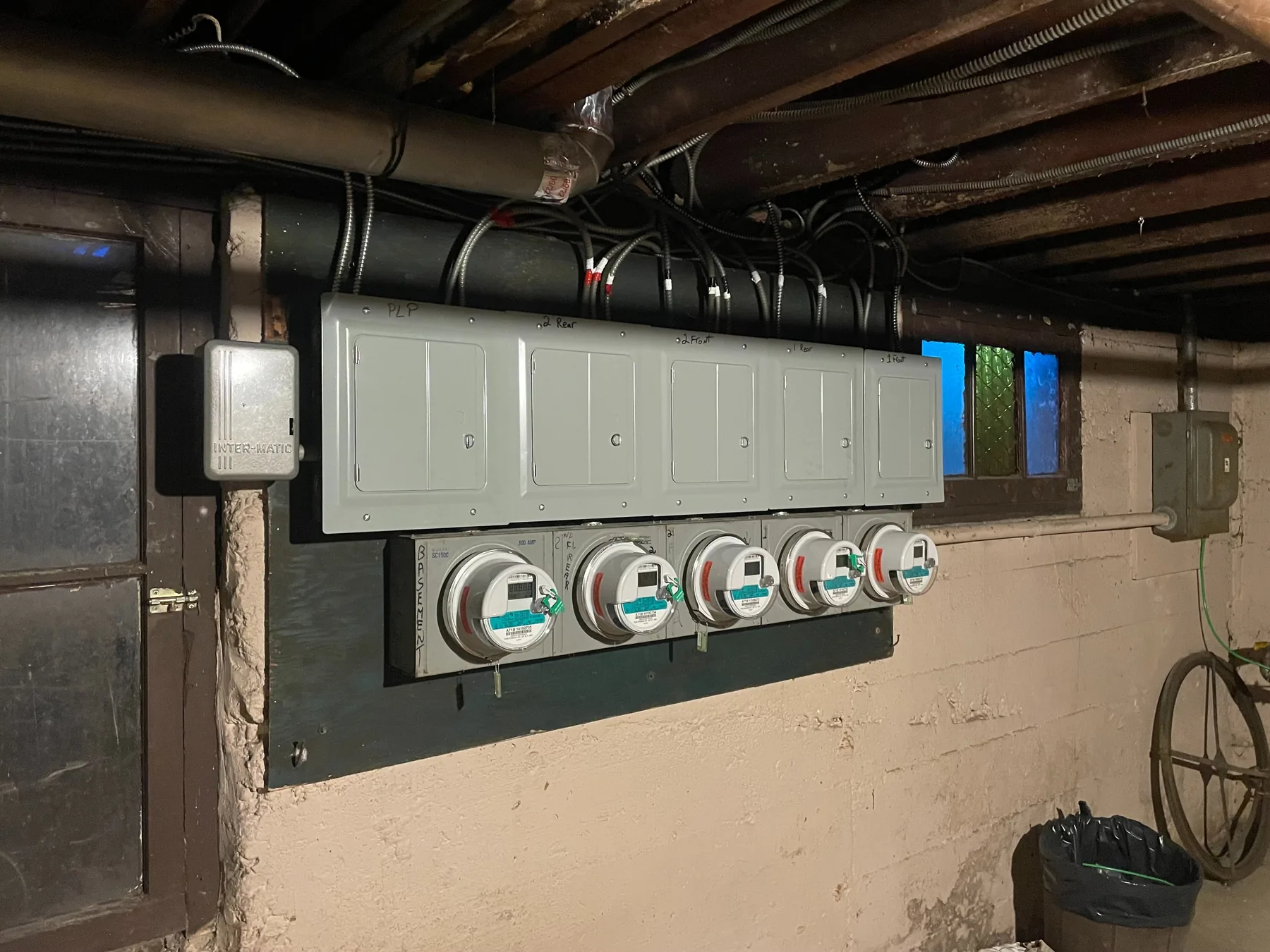 A bank of electric meters and disconnects installed on a basement wall
